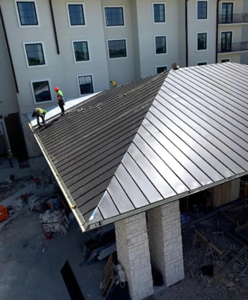 Crew installing standing seam metal roof panels on a commercial project in Arnold